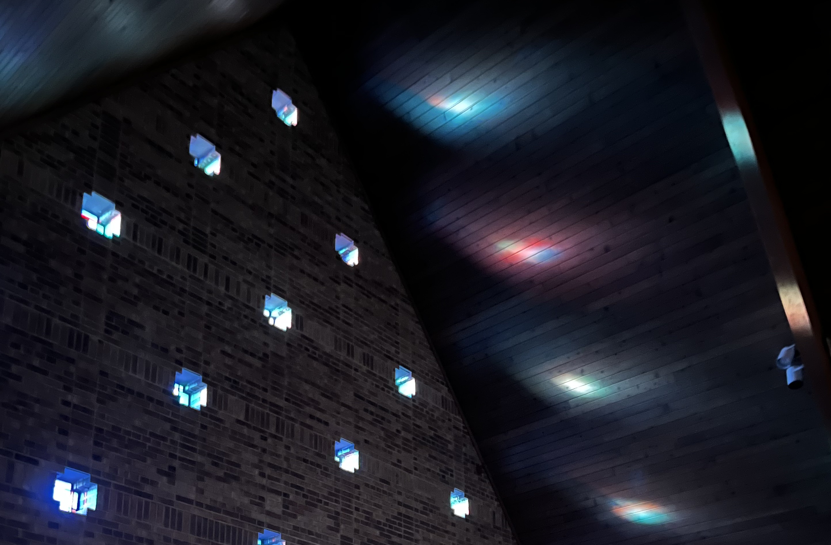 Stained glass windows in the sanctuary casting light on the ceiling